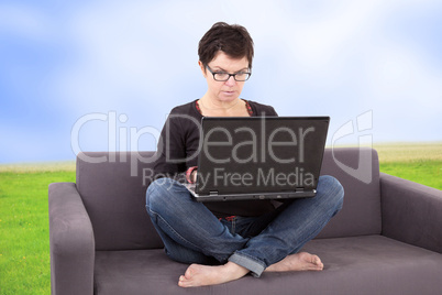 Woman sitting with laptop relaxing on the sofa