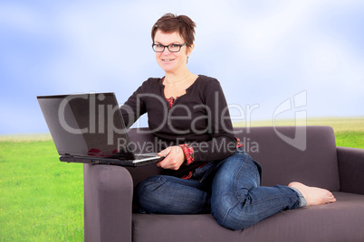 Woman sitting with laptop relaxing on the sofa