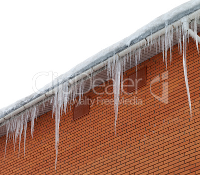 Snow-covered roof with icicles on white background