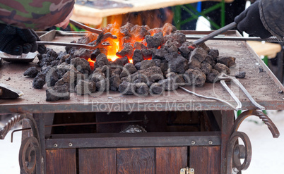 Craftsman blacksmith warming a piece of iron in the fire