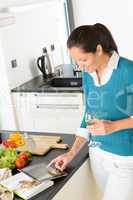 Woman searching recipe tablet kitchen vegetables book
