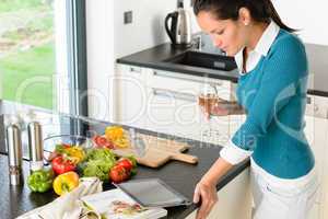 Young woman reading tablet recipe kitchen cooking