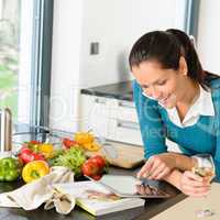 Smiling woman searching recipe tablet kitchen vegetables