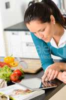 Woman looking tablet reading recipe kitchen vegetables