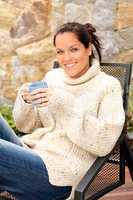 Smiling woman drinking tea patio sweater relaxing