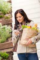 Young woman holding groceries vegetables shopping phone