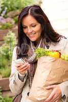 Smiling woman shopping vegetables mobile phone sms