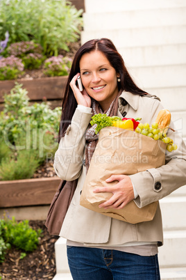 Happy woman shopping vegetables calling cell phone