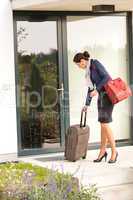 Businesswoman leaving house traveling carrying baggage hurried