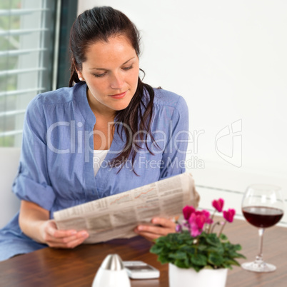 Woman reading newspaper relaxing wine living room