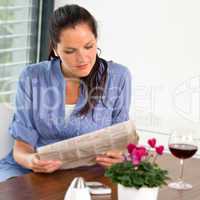 Woman reading newspaper relaxing wine living room