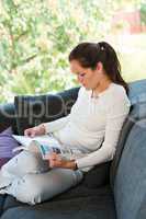 Young woman reading magazine living room couch