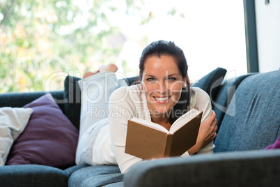 Smiling woman resting reading sofa learning domestic