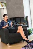 Happy woman relaxing armchair text messaging wine