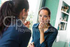 Young woman applying lipstick make-up bathroom