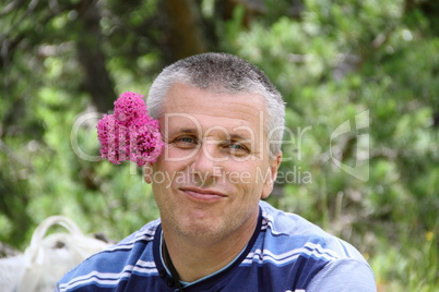 A handsome man with a pink flower behind the ear