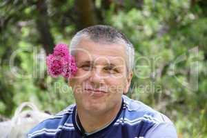 A handsome man with a pink flower behind the ear