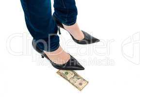 Woman in stilettos standing over ten dollar note