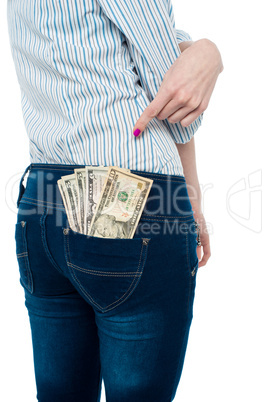 Woman pointing at dollar notes in her back pocket