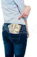 Woman pointing at dollar notes in her back pocket