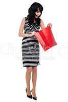 Young woman searching for her gift inside bag