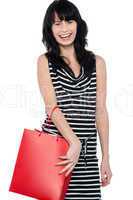 Joyous brunette posing with red shopping bag
