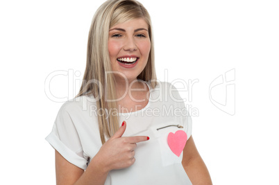 Pretty teen pointing towards pink paper heart