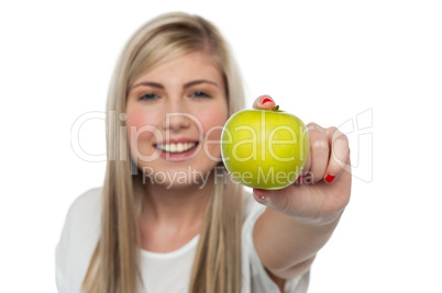 Smiling girl displaying fresh green apple to the camera