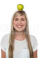 Smiling woman balancing an apple on her head