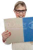 Excited teen girl holding note book close to her
