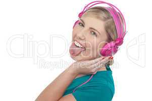Woman with headphones on sticking her pierced tongue out