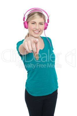 Young girl enjoying music and pointing at you