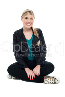 Cheerful teenager seated on floor, legs crossed