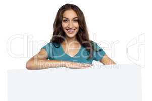 Young casual woman behind blank ad board