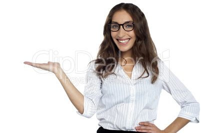 Joyous woman in spectacles posing with open palm