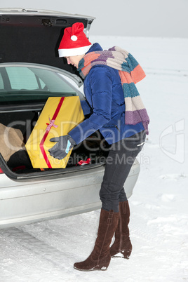 Woman standing by the open trunk and invites gift