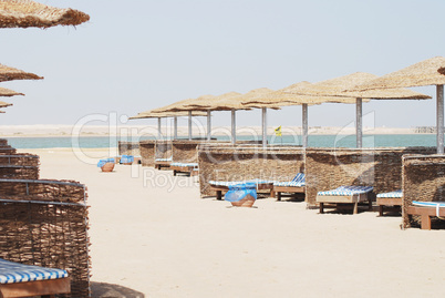 empty beach chair with straw sunshade at the sea