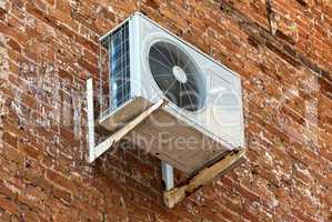 Air conditioning heat pump mounted on old brick wall