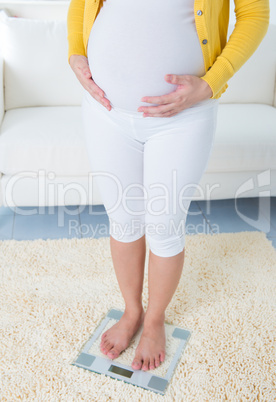 Pregnant woman measuring her weight through weighing scale