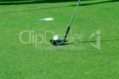 Golf ball and putter on green