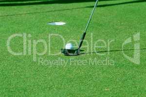 Golf ball and putter on green
