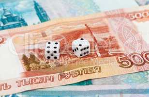 Two dice laying over a pile russian money