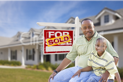 Father and Son In Front of Sold For Sale Sign and House