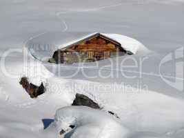 Timber hut nearly completely under the snow
