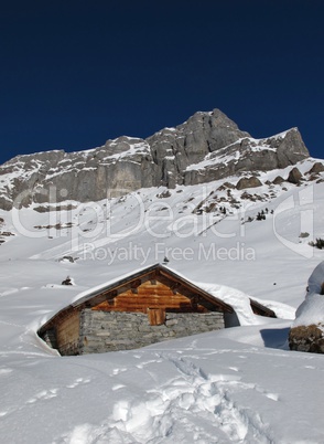 Snow covered timber hut, mountain named Eggstock