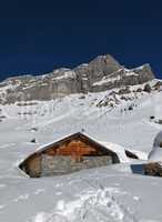 Snow covered timber hut, mountain named Eggstock