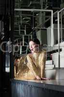 Beauty woman in gold dress posing on bar table