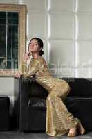 young brunette woman in gold dress on sofa
