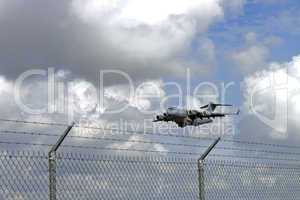 Aircraft C-17 over security fence