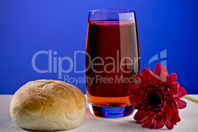 A soft roll and a glass of fruit sy